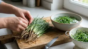 Mani che puliscono gli agretti su un tagliere, con ciotola d’acqua e scolapasta pronti per il lavaggio