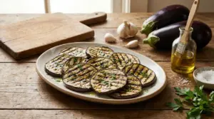 Fette di melanzane grigliate su un piatto con olio, aglio e prezzemolo su tavolo rustico