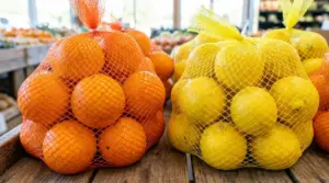 Reti arancioni con arance e reti gialle con limoni esposte nel reparto ortofrutta di un supermercato
